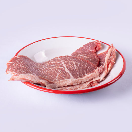 dos filetes de presa iberica fresca sobre plato blanco y filo rojo