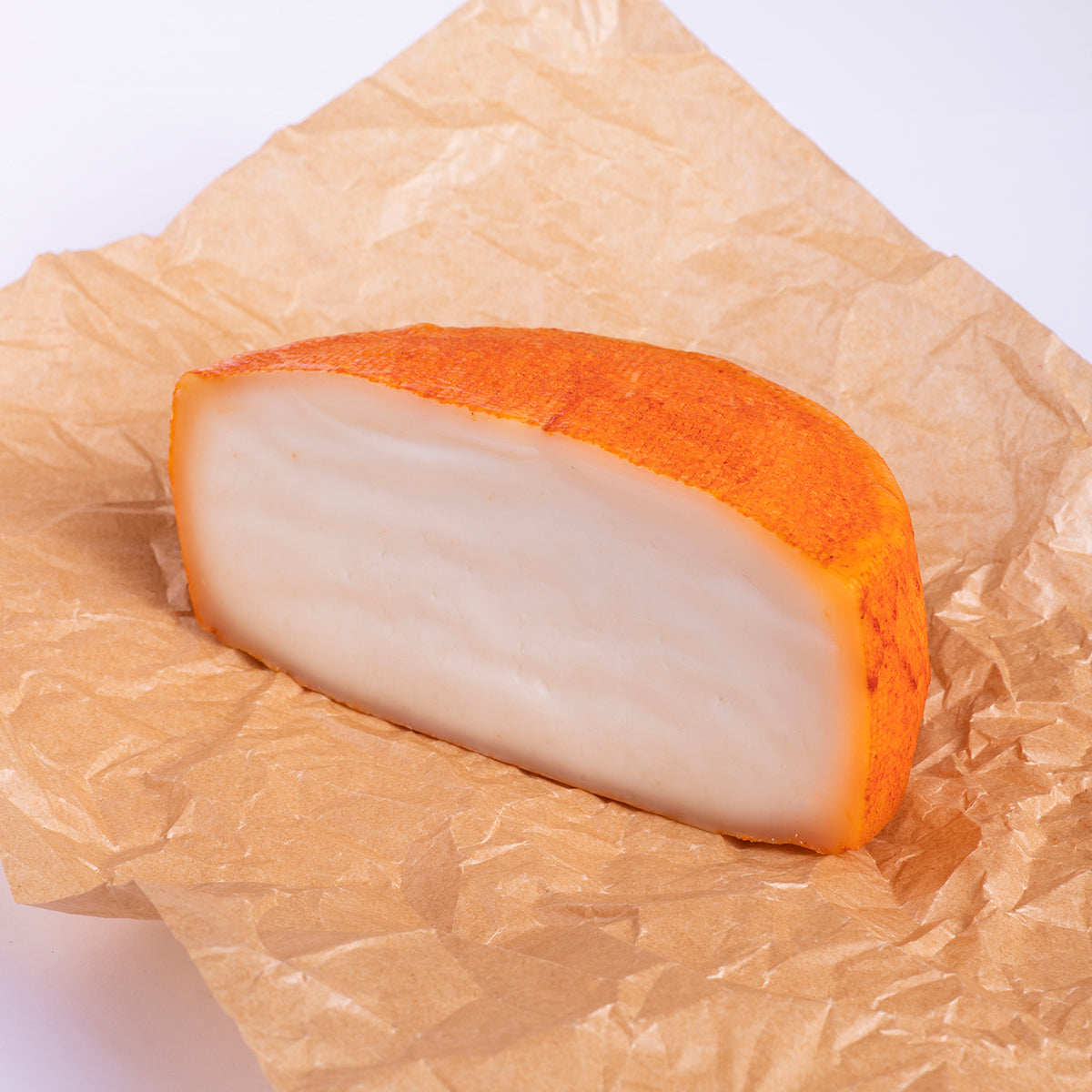 medio queso puro de cabra con corteza de pimenton e interior blanco, sobre papel alimentario